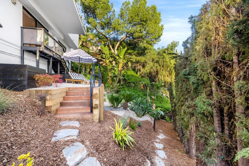 jardín con camino de sementó y hay arboles y una casa