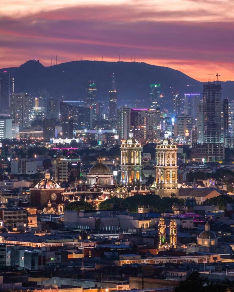 atardecer de puebla cerro al fondo cielo naranja y luces de la ciudad y edificios 